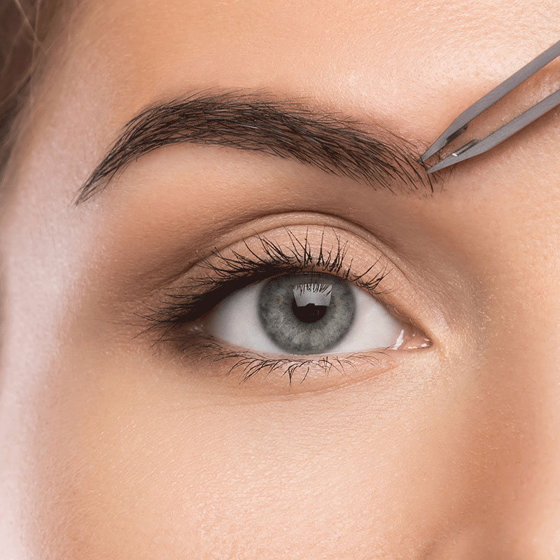 Wimpern und Augenbrauen zupfen Nahaufnahme von einem Auge und eine Pinzette, die die Augenbrauen zupft